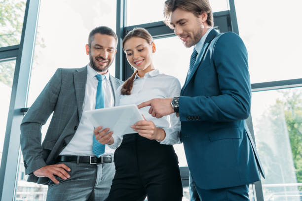 istock bottom view of happy business people using tablet together at modern office 1016605898