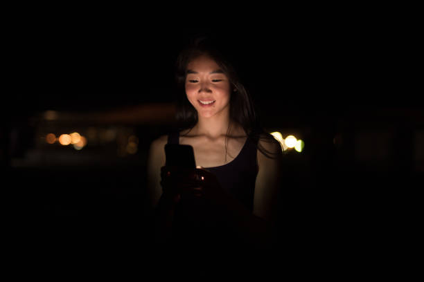 istock Happy Asian Woman Outdoors At Night Using Mobile Phone 1016611514