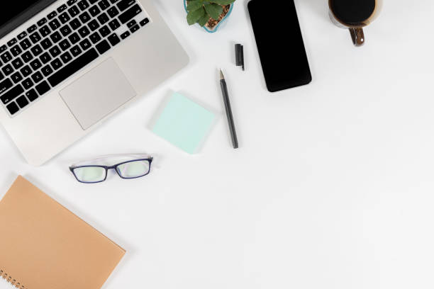 istock Office table with laptop computer, smartphone, pen, notebook and coffee on isolated pure white background / Laptop and tablet mockup concept. (Selective Focus) 1016614666