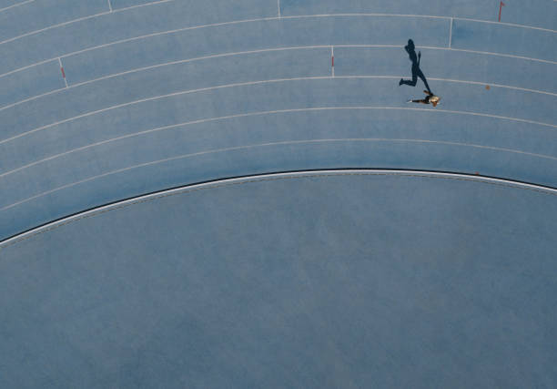 Aerial view of an athlete running on track Sprinter running on athletic track. Top view of a sprinter running on race track in a stadium with shadow falling on the side. lane marker stock pictures, royalty-free photos & images
