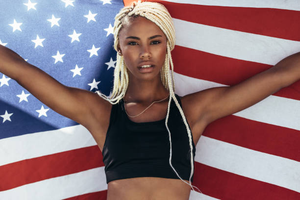 istock Female athlete holding american flag behind her 1016615212