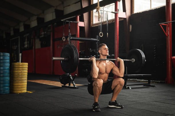 hombre musculoso durante su entrenamiento de levantamiento de pesas en el gimnasio - body building gym human muscle effort fotografías e imágenes de stock