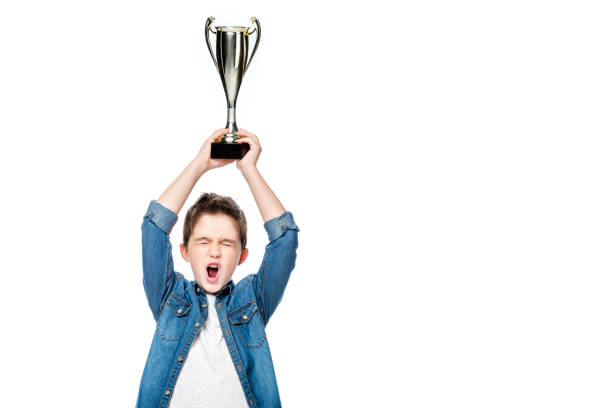 istock schoolboy screaming and holding winner cup above head isolated on white 1016623216