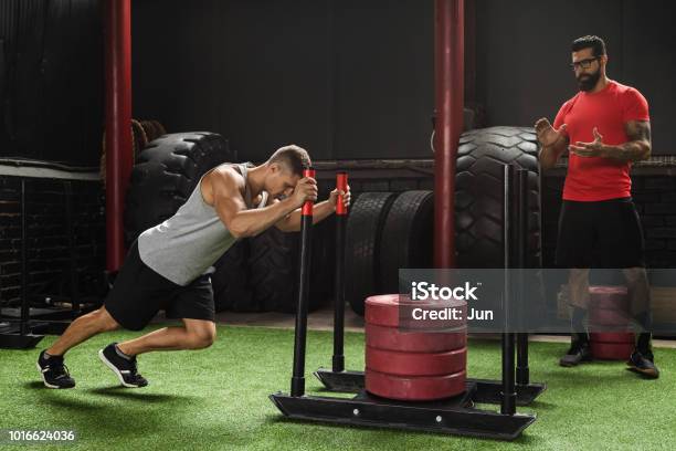 Strong Sportsman During Sled Push Exercise Stock Photo - Download Image Now - Sled, Pushing, Exercising