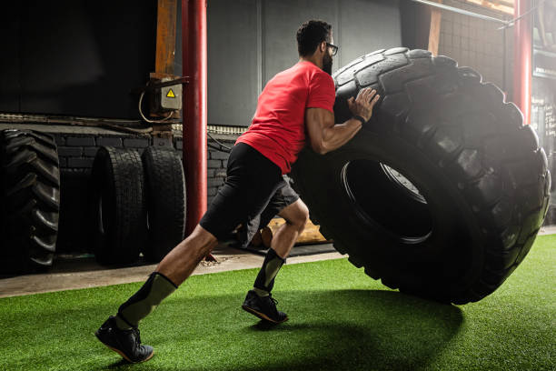 fuerte deportista haciendo un ejercicio de tirón neumático - throwing wheel fotografías e imágenes de stock