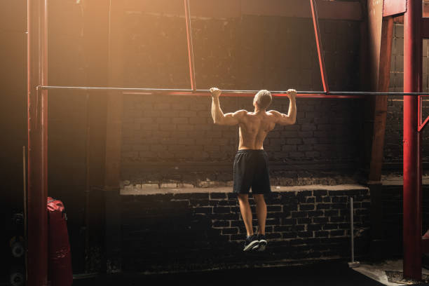 Strong man doing pull up exercise in the gym Man doing pull up exercise. Sportsman during his workout in the gym. gymnastics bar photos stock pictures, royalty-free photos & images
