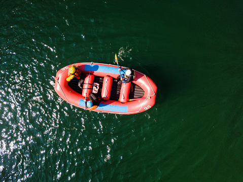Drone point of view of a group men and women rafting in a calm river