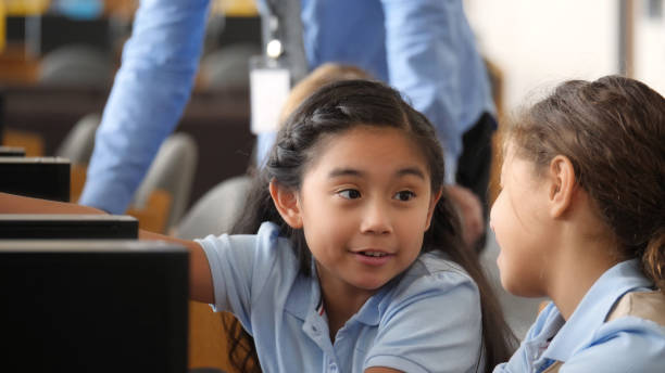 istock Little girl enjoys working with friend on computer lab assignment 1016651394
