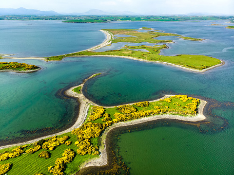 Aerial view of vivid emerald-green waters and small islands near Westport town along the Wild Atlantic Way, County Mayo, Ireland.