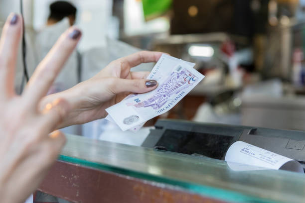 Woman makes purchase in chinatown Unrecognizable woman gives Singapore dollars to pay for meal while in chinatown. singapore cash stock pictures, royalty-free photos & images