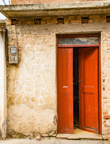 パワーメータで黄色い壁に赤いドアを開く。壁面の看板がスペイン語で「販売のための家」 - door open house facade ストックフォトと画像
