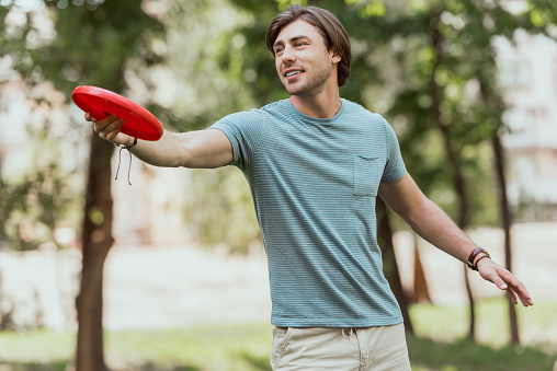 handsome man throwing frisbee disk in park