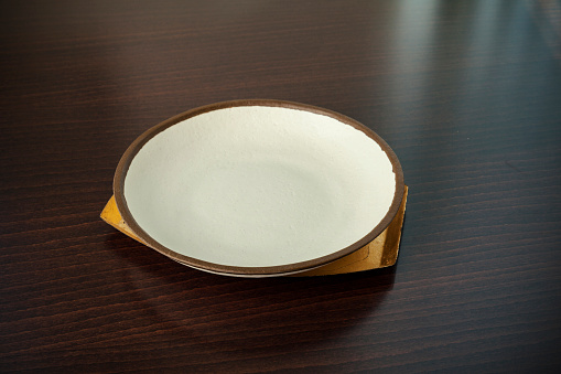 empty white plate on a wooden table, close up