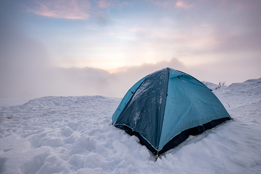 Camping blue tent at snowy hill in foggy on vacation