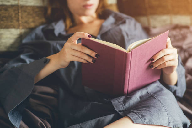 istock Woman relaxing in bed with her favorite book. 1016677518