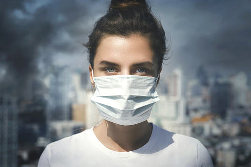 Mujer con mascarilla debido a la contaminación del aire en la ciudad photo