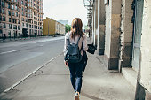 Back view of a hipster girl walking on city street.