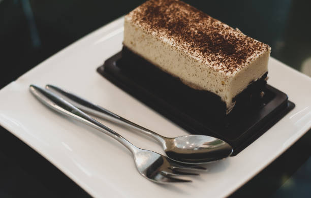 istock Cheese cake served on white plate together with silverware, ready to eat, on the dessert prinkle with cocoa powder 1016697794