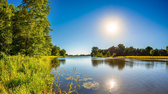 Autumn scene from river, river shore reflecting at blue water surface at sunny autumn day, late afternoon, no people