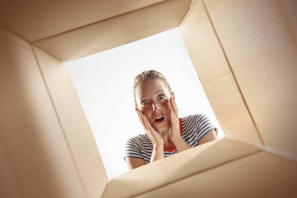 istock Woman unpacking and opening carton box and looking inside 1016715868
