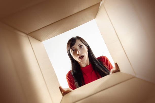 istock Woman unpacking and opening carton box and looking inside 1016720238