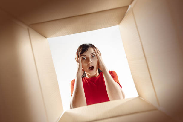 istock Woman unpacking and opening carton box and looking inside 1016720312