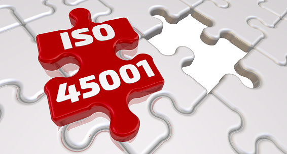 Folded white puzzles elements and one red with text ISO 45001 - is an International Standard that specifies requirements for an occupational health and safety management system. 3D Illustration
