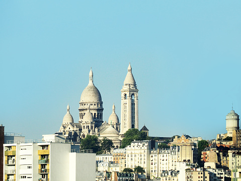 Paris, France. Montmartre against the blue sky among residential modern areas. Basilica of Sacre Coeur (Basilica of the Sacred Heart). Roman Catholic church