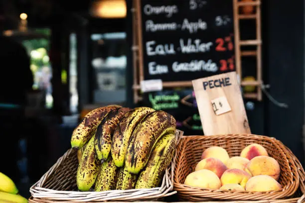 Fruitstand with Bananas, Pineapple and Peaches with a smoothie menu in the blurred background