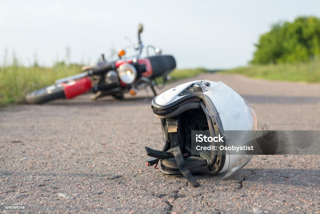 Photo of helmet and motorcycle on the road, the concept of road accidents Photo of helmet and motorcycle on road, the concept of road accidents Motorcycle Stock Photo