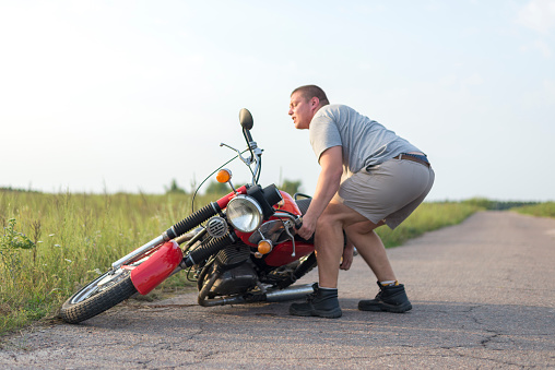 A man lifts a heavy motorcycle that fell after an accident