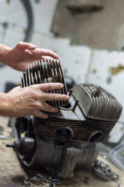 istock A man fixing a motorcycle motor in a garage, hands holding a cylinder 1016771760