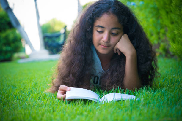 istock young girl reading a book on the lawn 1016772066