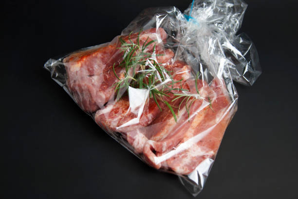 istock Cooking baking plastic bag. No pastic concept. Fresh pork meat steake packaged in a sleeve with spices, for baking is ready for baking, isolated on black background. Top view. 1016793424
