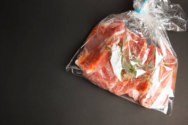 istock Cooking baking plastic bag. Fresh pork meat steake packaged in a sleeve with spices, for baking is ready for baking, isolated on black background. Top view. Copy space. 1016793426