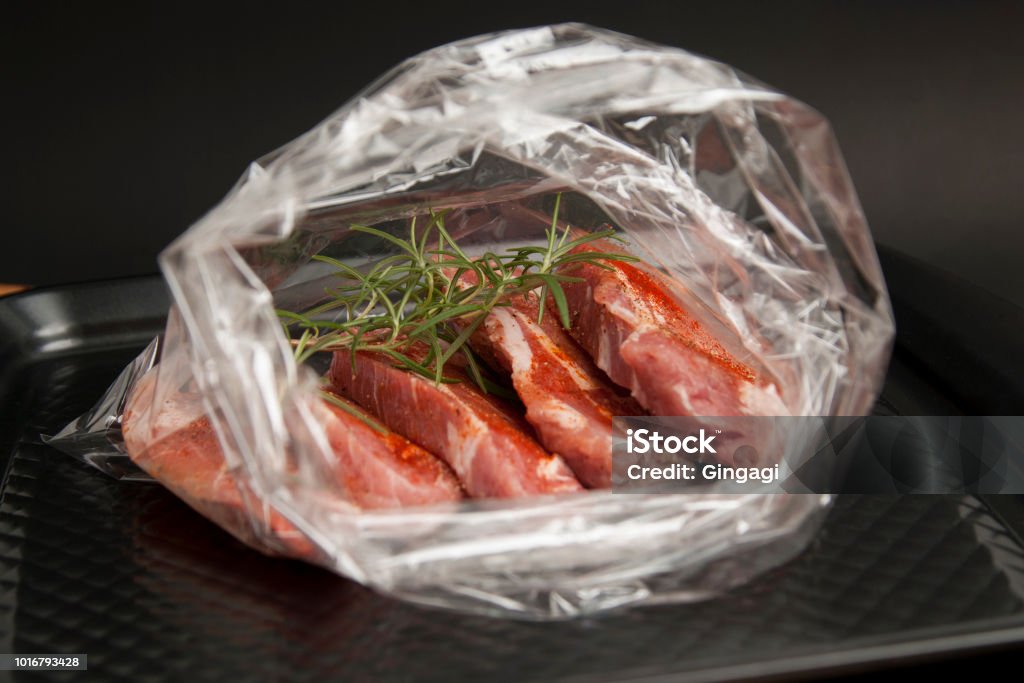 Cooking baking plastic bag. No pastic concept. Fresh pork meat steake packaged in a sleeve with spices, for baking is ready for baking, isolated on black background. Top view. Cooking baking plastic bag. No pastic concept. Fresh pork meat steake packaged in a sleeve with spices, for baking is ready for baking, isolated on black background. Bag Stock Photo