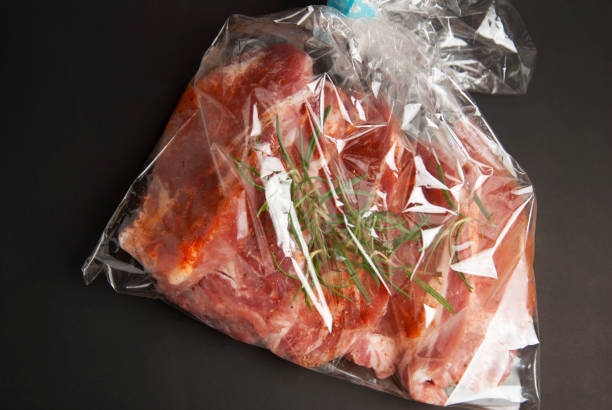 istock Cooking baking plastic bag. No pastic concept. Fresh pork meat steake packaged in a sleeve with spices, for baking is ready for baking, isolated on black background. Top view. 1016793430