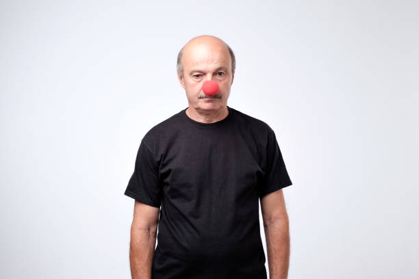 istock Senior man in black tshirt standing with red clown nose in depression. 1016798770
