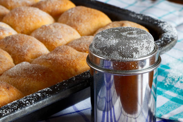 sugared poppy and plum cakes on baking tray with sugar bowl and rolling pin