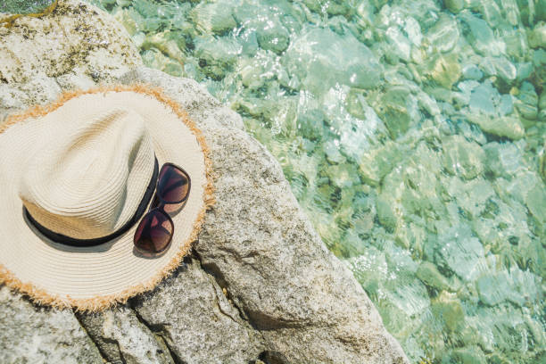 Female accessory, straw sunhat, glasses on beach. Summer vacation.