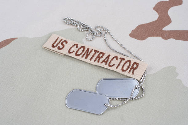 istock US CONTRACTOR branch tape with dog tags patch on desert camouflage uniform 1016877464
