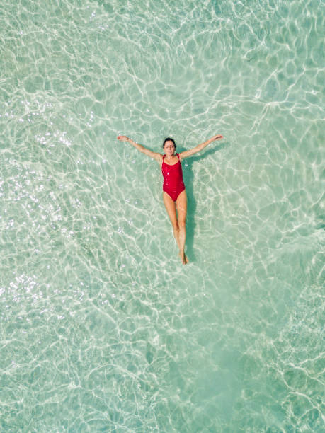 colpo aereo di donna che si rilassa in spiaggia - galleggiare sullacqua foto e immagini stock