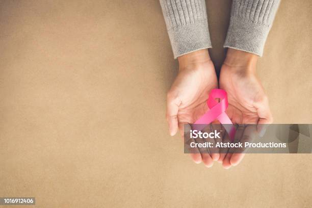 Woman Hands Giving Satin Pink Ribbon Supporting Symbol Of Breast Cancer Awareness Campaign In October Stock Photo - Download Image Now