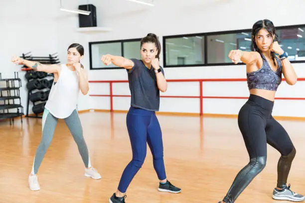 Determined women in sportswear punching the air in gym