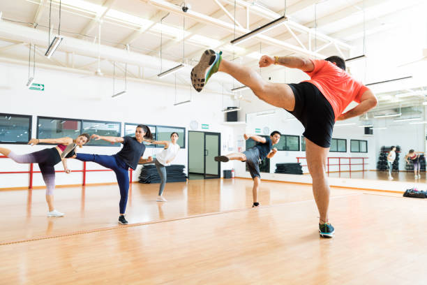 Instructor And Clients Kickboxing In Dance Class At Gym Full length of male instructor and clients kickboxing in dance class at gym kickboxing photos stock pictures, royalty-free photos & images