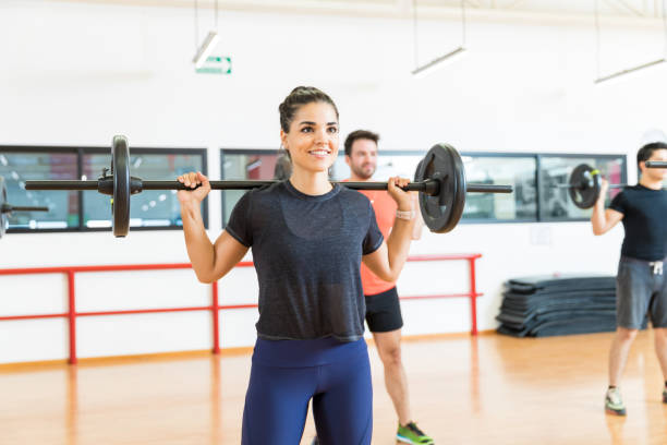 istock Woman Lifting Barbell While Looking Away In Gym 1016953108