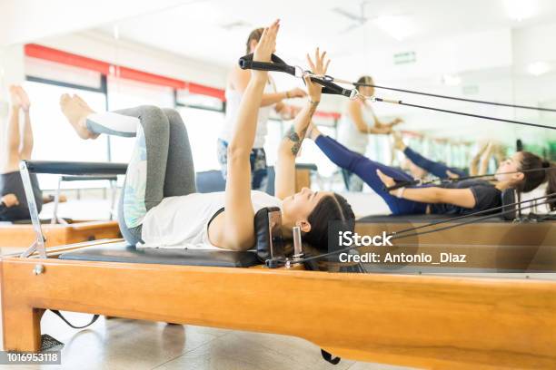 Woman Pulling Resistance Bands On Reformer Machine Stock Photo - Download Image Now - Pilates Machine, Pilates, Women