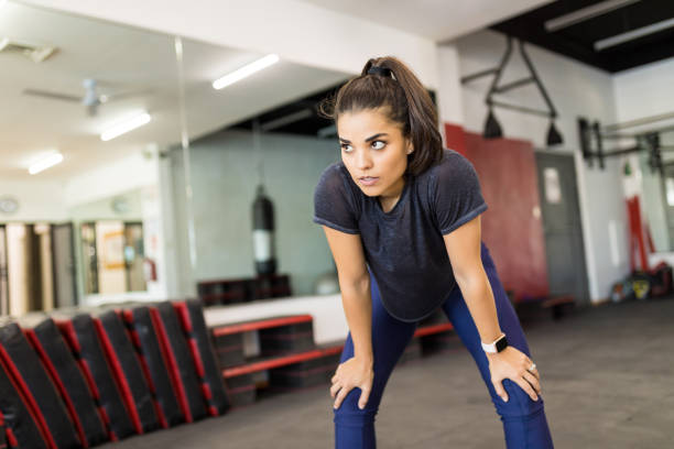 istock Exhausted Woman Leaning On Knees In Gym 1016969058