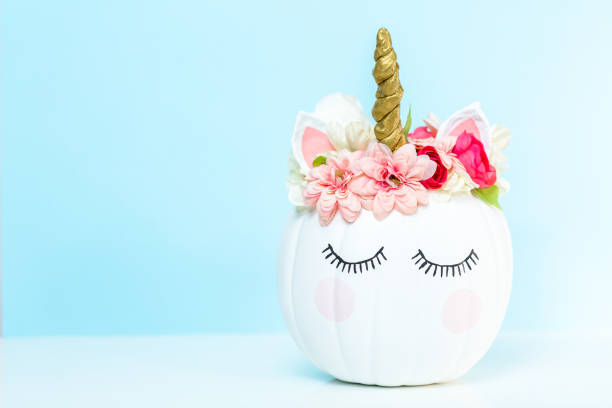 Craft pumpkin painted white and decorated with pink flowers Craft pumpkin painted white and decorated with pink flowers as unicorn on blue background. pumpkin decorating stock pictures, royalty-free photos & images