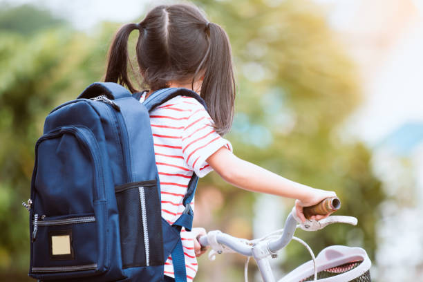 Cute asian child girl with backpack biking a bicycle and going to school Back to school. Cute asian child girl with backpack biking a bicycle and going to school with fun bicycle cycling school child stock pictures, royalty-free photos & images